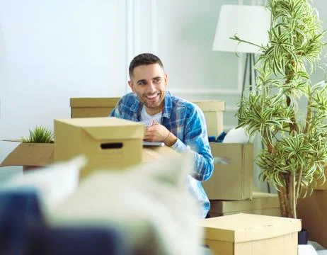A moving man sitting on the floor in empty apartment, Among the Boxes, Checking Stock Photos