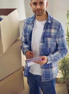 A moving man sitting on the floor in empty apartment, Among the Boxes, Checking Stock Photos