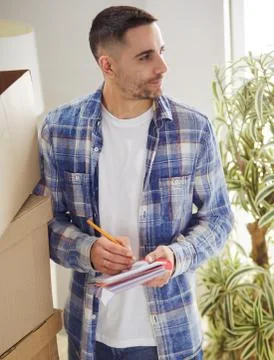 A moving man sitting on the floor in empty apartment, Among the Boxes, Checking Stock Photos