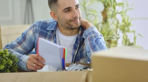 A moving man sitting on the floor in empty apartment, Among the Boxes, Checking Stock Photos