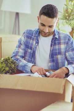 A moving man sitting on the floor in empty apartment, Among the Boxes, Checking Stock Photos