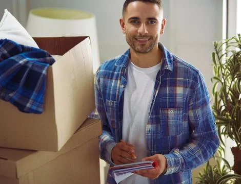 A moving man sitting on the floor in empty apartment, Among the Boxes, Checking Stock-Fotos