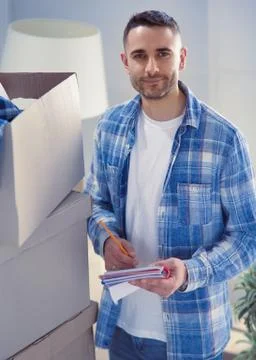 A moving man sitting on the floor in empty apartment, Among the Boxes, Checking Stock Photos
