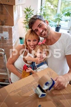 Moving in new house. mother and father with a toddler girl packing box.. Stock Photos