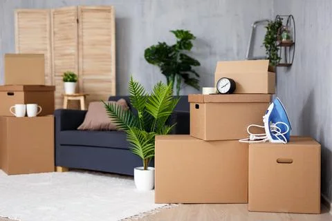 Moving to new house - stack of cardboard boxes with belongings in living room Stock Photos