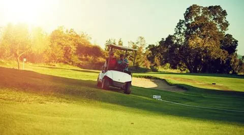 Moving on to the next teeing ground. two golfers riding in a cart on a golf 스톡 사진