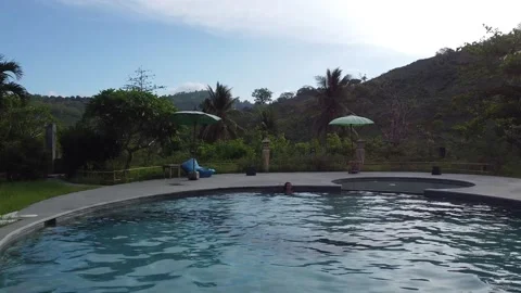 MOVING OVER POOL AND LIFTING OFF TOWARDS MOUNTAINS Stock Footage 221303675