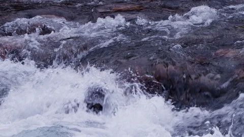 Moving over wild foaming river water with grey and red stones in cloudy weather Video stock 108915929