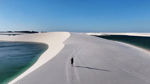 Moving Past a Lone Walker on a Lagoon-Bordered Sand Spit Stock Footage 342444653