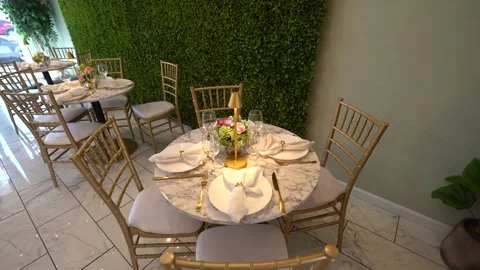 Moving past a round table set with gold cutlery and a small lamp Stock Footage 345552061