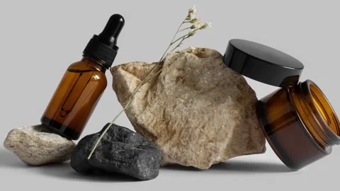 Moving picture of dropper glass bottle, jar of cream, flower branch on rocks Stock Footage 155106974