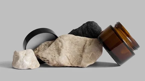 Moving picture of opened brown glass jar with black cap on rocks Stock Footage 155106978