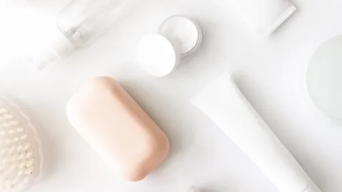 Moving picture of squeeze tube, jar of cream, soap, body brush flat lay Stock Footage