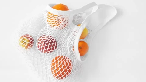 Moving picture of white mesh bag with fruits flat lay on white background Stock Footage 154952713
