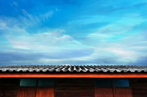 Moving planes, cloudy blue sky and roof of wooden house Stock Photos