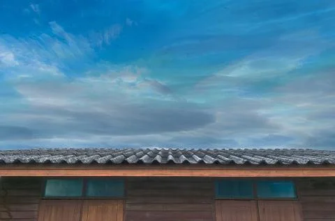 Moving planes, cloudy blue sky and roof of wooden house Stock Photos