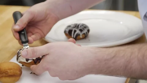 Moving the prepared donuts carefully into another plate Stock Footage 307340000