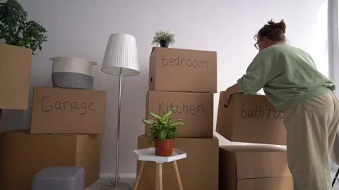 Moving, relocation and minimalism concept. A woman brings cardboard boxes with Stock Footage 154344761