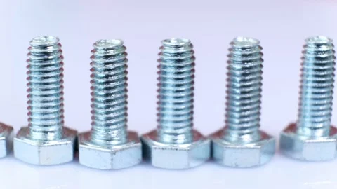 Moving row of galvanized metallic screws close-up, one of them is pink colored. Stock Footage 141149442