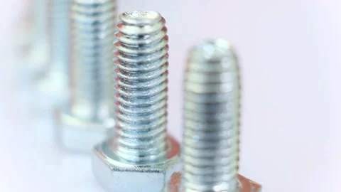 Moving row of galvanized metallic screws close-up, one of them is pink colored. Video stock 141332854