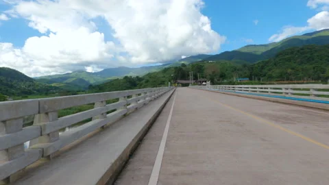 Moving scenery seen while riding bicycle on bridge with mountains and bright sky Video stock 135573902