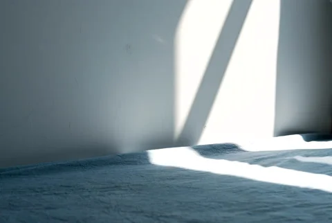 The Moving Shadow of Sunbeam Falling on Bed Against Wall Stock Footage 224315039
