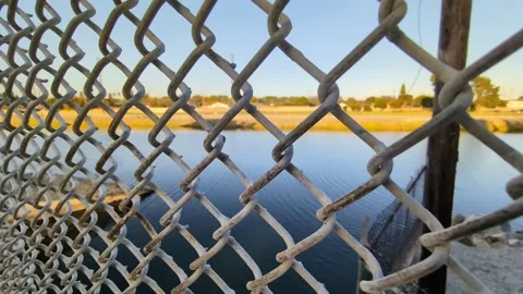 Moving shot of canal water through a wire mesh fence Stock Footage 337729604