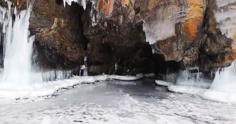 Moving shot. Cave with long icicles under the frozen rocks on Baikal lake Stock Footage 141021649