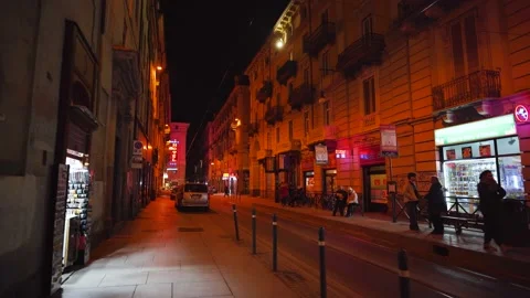 Moving shot of an empty illuminated red street at night with few people Stock Footage 235399692
