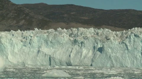 Moving shot sailing through icebergs in front of glacier wall Stock Footage 60139206