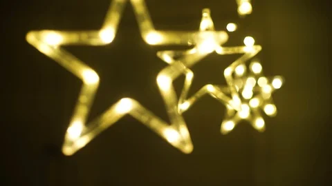 Moving shot with a shallow depth of feild through hanging golden star shaped LED Stock Footage 129516264