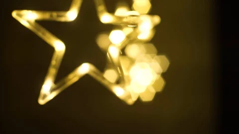 Moving shot with a shallow depth of feild through hanging golden star shaped LED Stock Footage 129516491