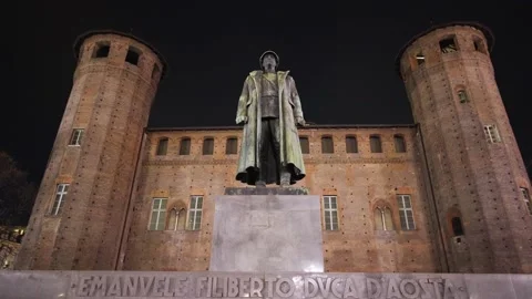 Moving shot of a statue of a man in a square at night with a castle Stock Footage 235398717