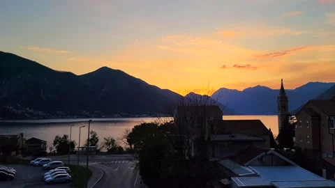 Moving Shot of Yellow Sunset with Mountains, Sea, Church, and Cars Stock Footage 237997830