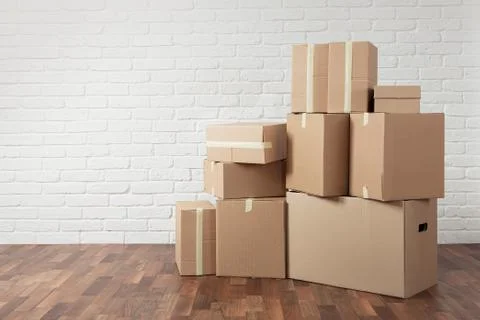 Moving in. Stack of cardboard boxes in the empty room with copy space Stock Photos