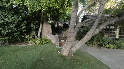 Moving through a backyard garden to a wicker patio lounge area Stock Footage 345543504
