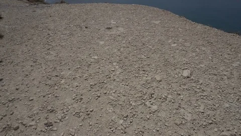 Moving towards the cliff edge and looking over blue sea. POV, handheld shot Stockbeeldmateriaal 76989109