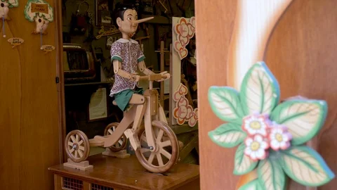 A moving toy of an human sized Pinocchio which is riding a tricycle made from Video stock 105891065