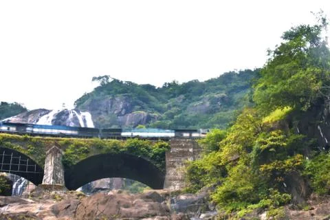 A moving train passing in front of a waterfall in goa Foto stock