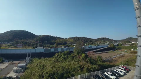Moving train showing the rural landscape and a highway near Hiroshima, Japan 스톡 동영상 335523235