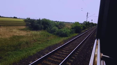 Moving train window POV shot of passing green landscape and railway tracks in 스톡 동영상 331063907