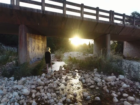 Moving Under a Bridge with a Gentle Stream at Sunset Stock Footage 79148899