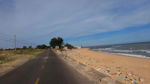 Moving vehicle window shot of an empty sandy beach littered with ocean debris. Stock Footage 344398894
