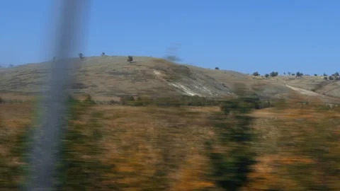 Moving view of expansive dry landscape, hillside with sparse trees, clear blue 库存影片 339866040
