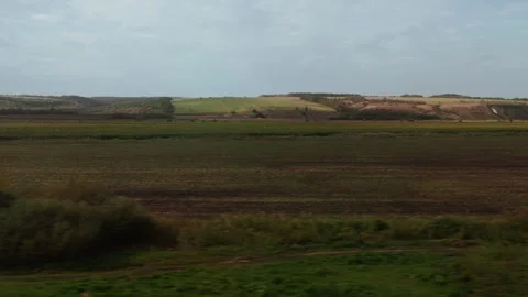 Moving view from a train of rolling hills and agricultural fields. A distant Stock Footage 322095189