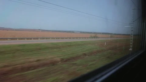 Moving view from train shows parallel road and rural landscape. Power lines and Stock Footage 320606024