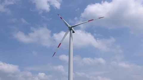 Moving wind turbine (wind mill) with a cloudy but blue sky in the background Stock Footage 92890551