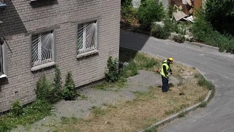 Mowing the grass with a lawn mower. A worker tends the lawn near a house Vídeo Stock 338029710