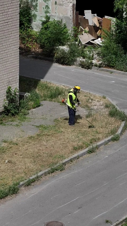 Mowing the grass with a lawn mower. A worker tends the lawn near a house Video stock 338029713