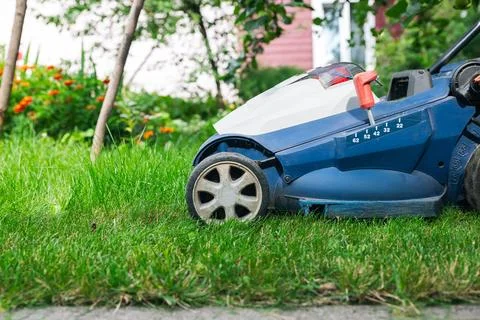 Mowing or cutting the very long grass with a green lawn mower in the summer s Stock Photos